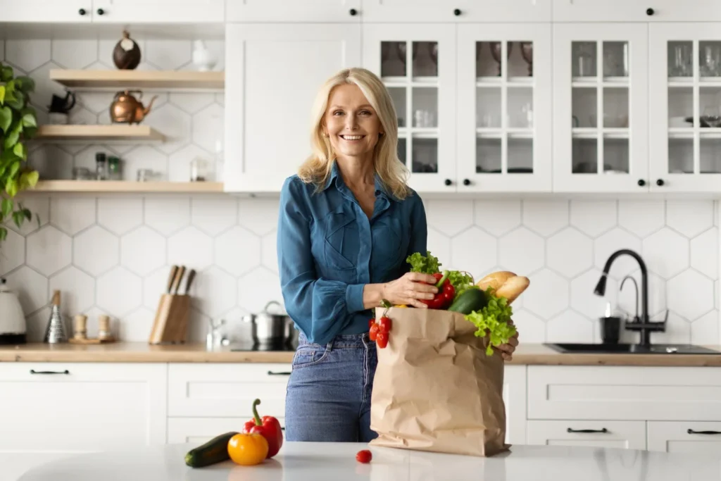 Woman unpacking fresh organic vegetables from a grocery bag in her kitchen