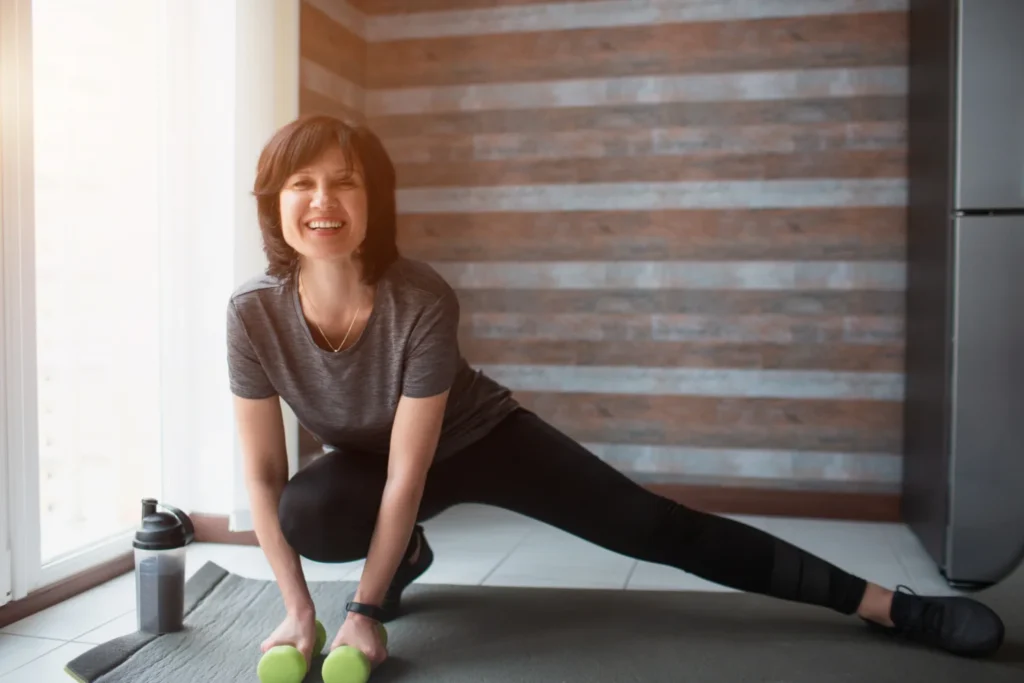 Fit mature woman exercising with dumbbells at home
