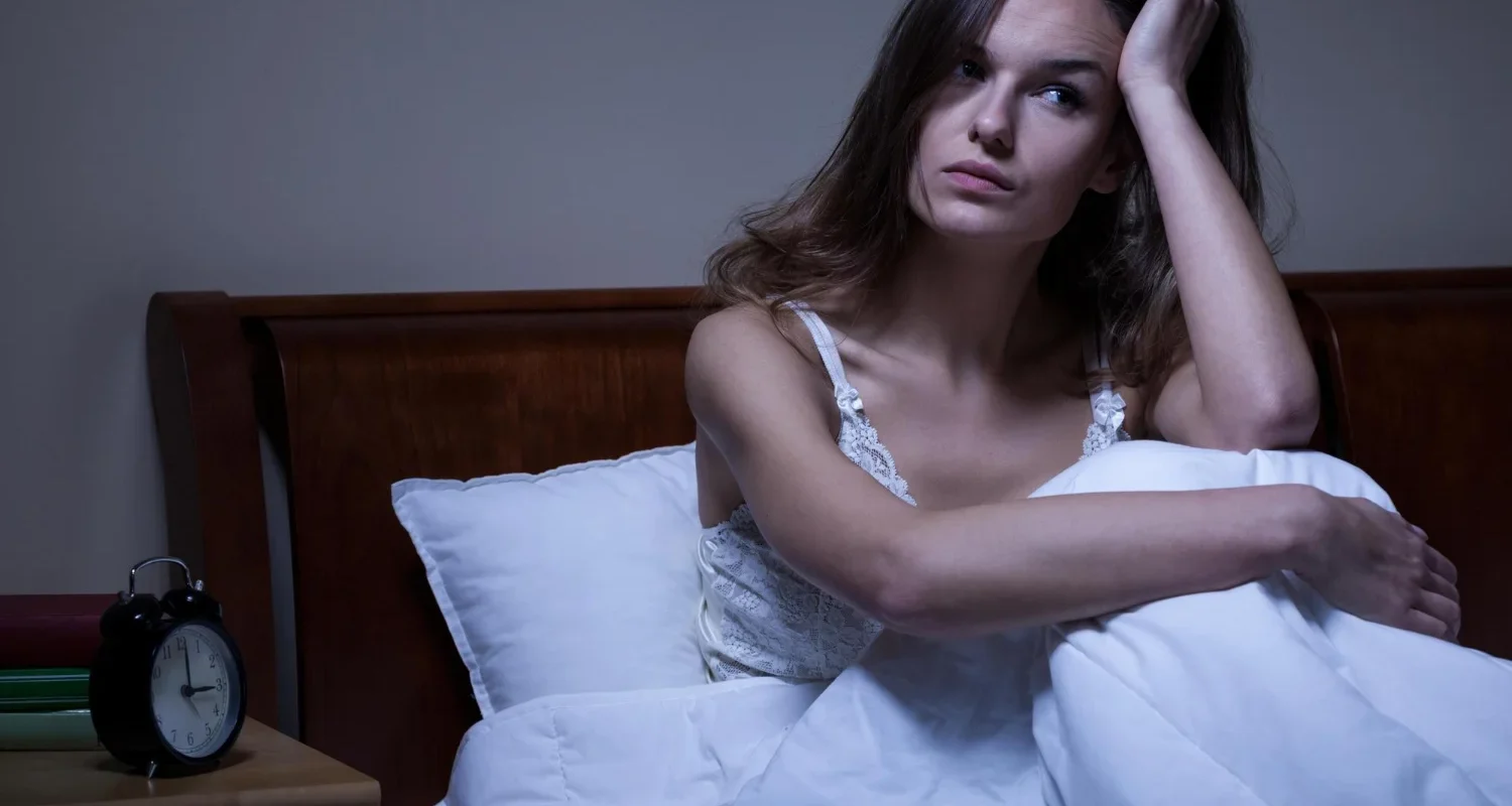 Woman sitting awake in bed at night